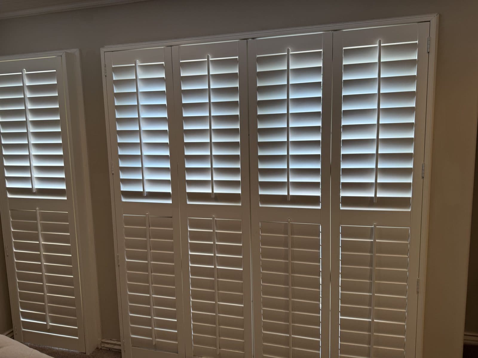 White shutters on an arched window above a sofa. Real AAA Shutter Repair job photo.
