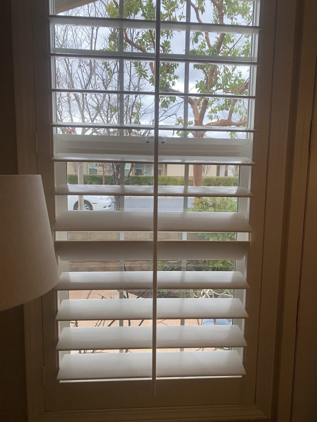 Close view of white cafe shutters above a tiled kitchen backsplash. Real AAA Shutter Repair job photo.