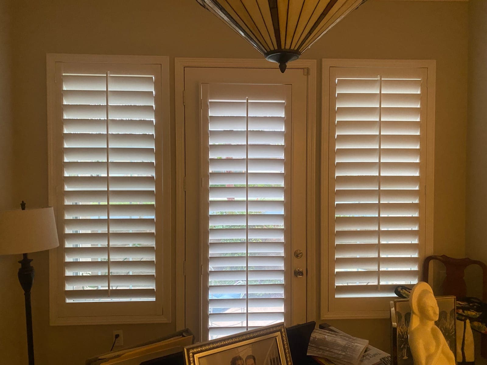White cafe shutters covering the lower half of a window above a sofa