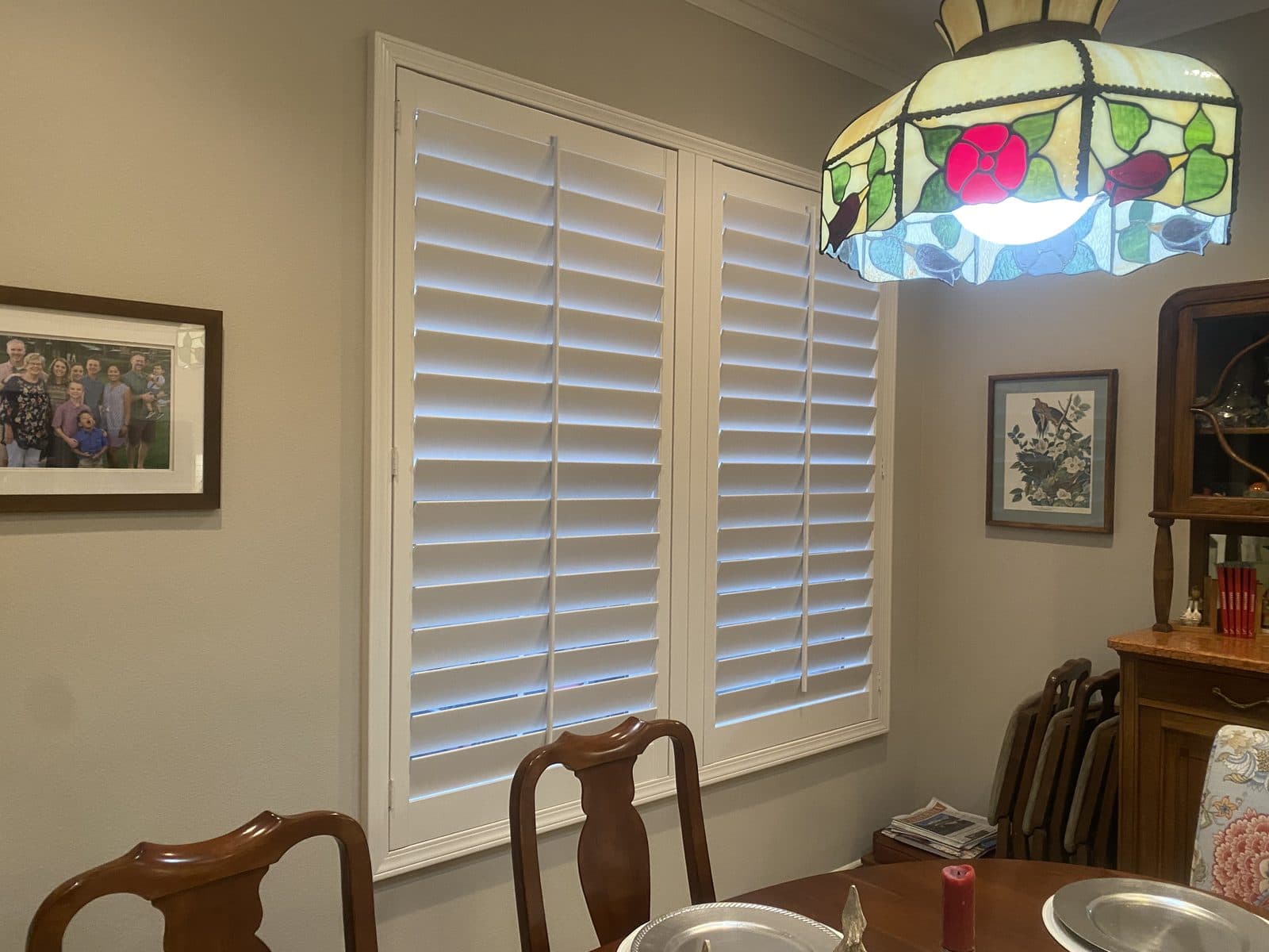 Roller shade mounted above white plantation shutters. Real AAA Shutter Repair job photo.