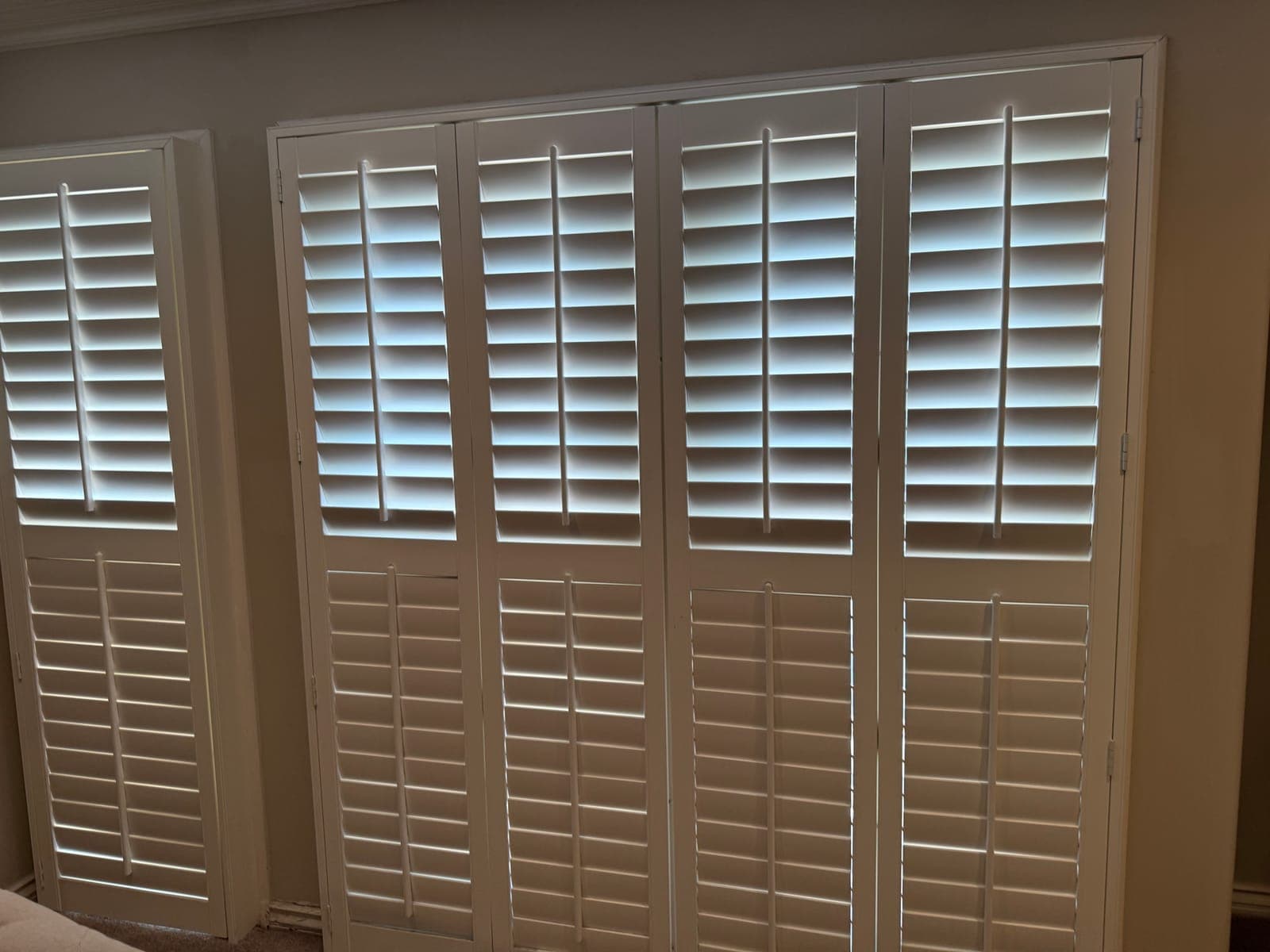 White plantation shutters on a sliding glass door with one panel open